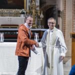 två män skakar hand, den ena är biskop och klädd i kyrkliga kläder